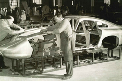 Master sheet metal worker Bert Brookes, in apron, affixes the magnesium/aluminum alloy panels to DP215 in 1963